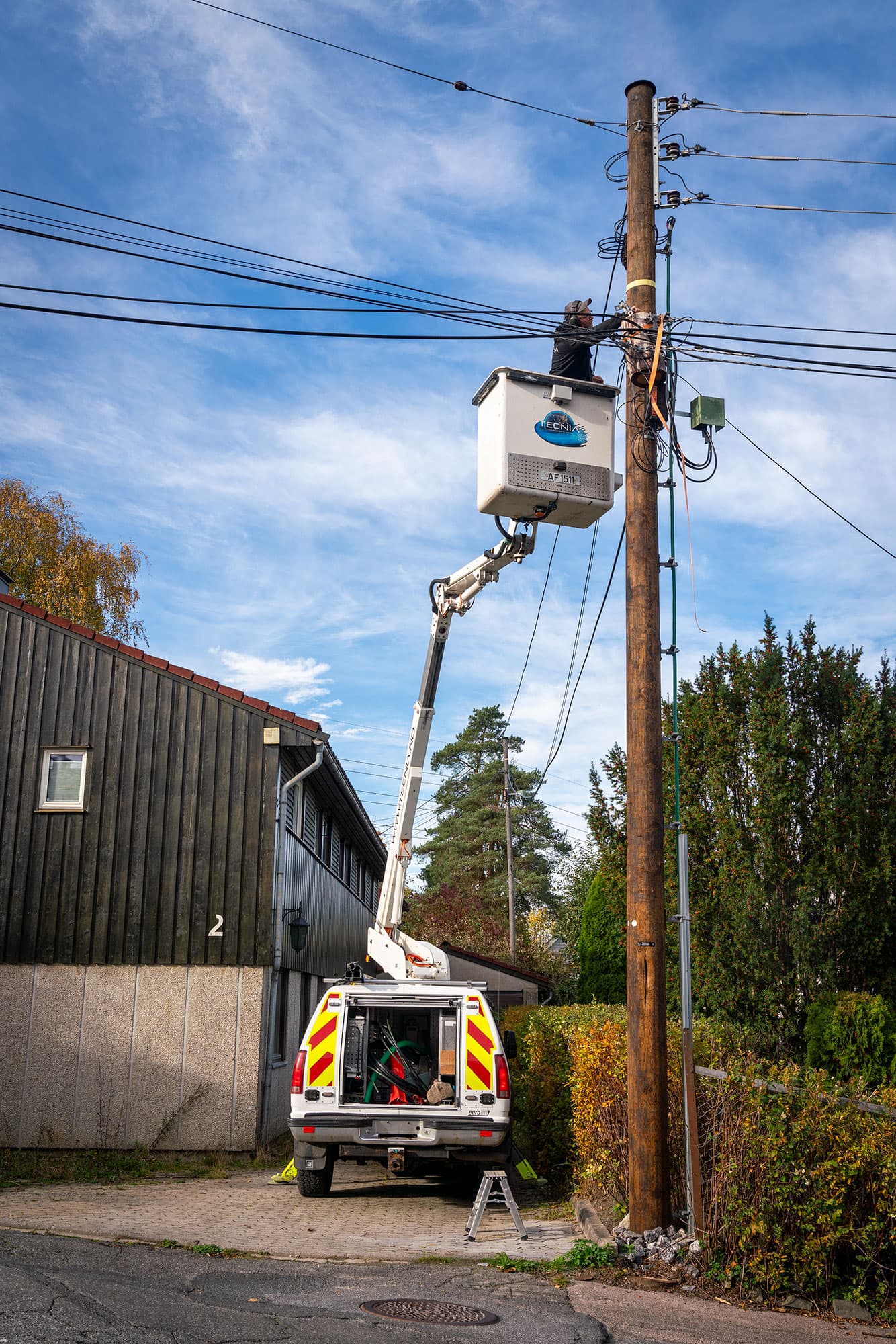 Tecnia AS - Lift med tekniker ved stolpe i solnedgang