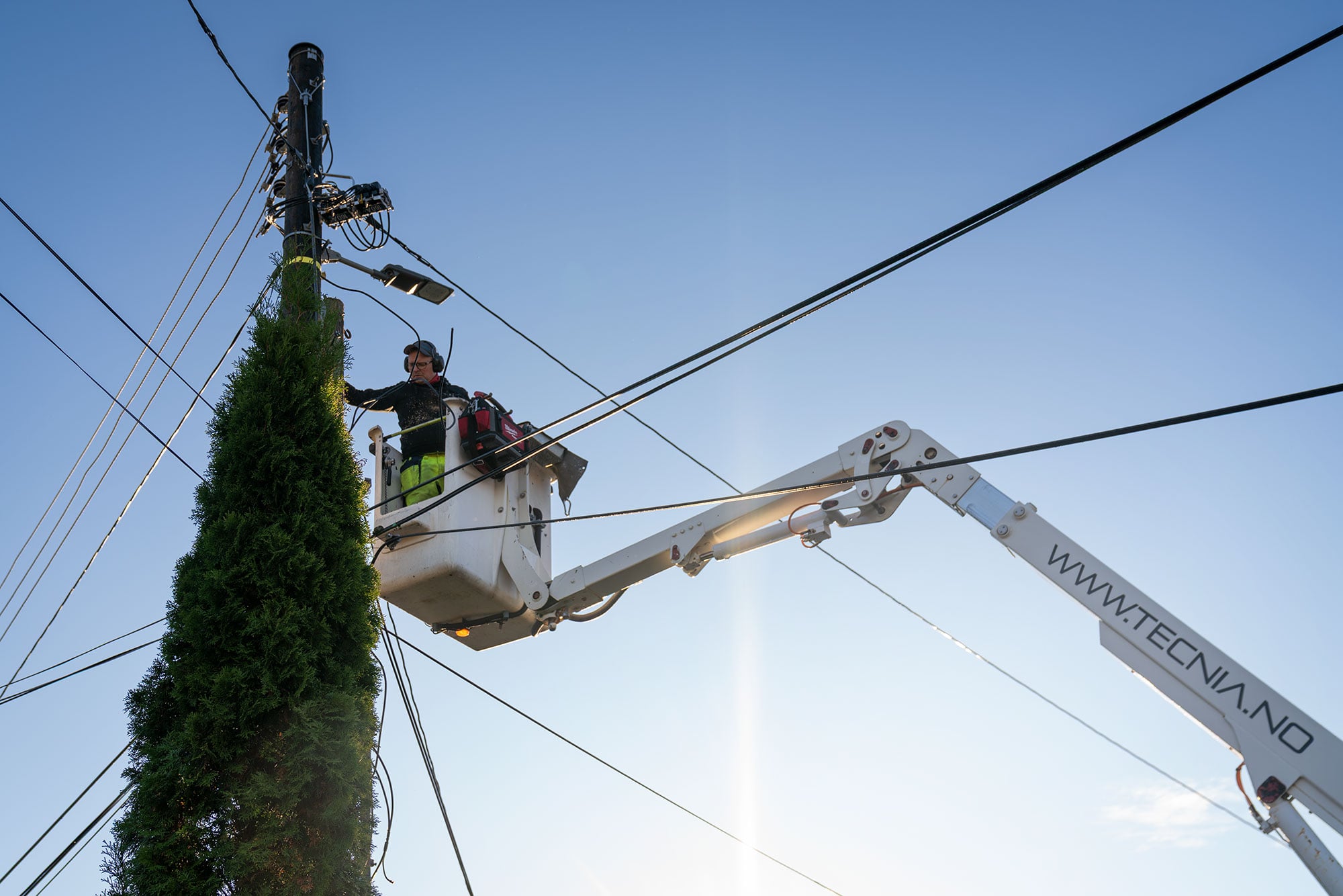 Tecnia AS - Liftarbeid ved telestolpe under blå himmel